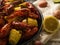 Pictured is a large black plate with boiled crayfish and corn. Half a lemon lies nearby. Light background. Bright colors. Close-up