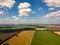 Picturesque aerial view of farmland in the countryside, blue sky with white clouds, colorful fields with different planted crops,
