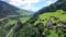 Picturesque aerial view of houses of small Swiss village Cavardiras in mountain valley in sunny summer day