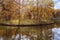 Picturesque autumn landscape, old ruined stone arch on the island with forest and river, colorful vivid foliage of trees