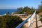 Picturesque and breathtaking oceanside landscape with grass and white wood guardrail on cliff by sea in Sydney, Australia