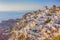 Picturesque Cityscape of Oia Village in Santorini Island Located on Red Volcanic Calderra at Daytime with Windmills on Background