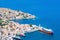 Picturesque detailed bird`s eye view on tiny colorful houses on rocks and group of boats near the Mediterranian sea on Greek isla