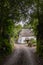 A picturesque Devon country lane surrounded by hedgerows with a thatched cottage in the distance