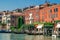 Picturesque embankment of the Grand Canal on a sunny summer day. Bright Venetian houses on the water, overgrown with bright greene