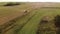 Picturesque flat countryside with farmland, bushes, reclamation ditch and vintage combine harvester reaping crops on a