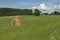 Picturesque hay runoff on a mown green field against a blue sky backgfound