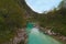 Picturesque landscape view of alpine Soca River. Emerald green water flows between mountains with dense forest