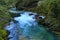 Picturesque landscape view of fast winding stream with turquoise water between big stones covered by moss in famous Vintgar Gorge