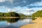 Picturesque meandering river landscape with rocky river banks and reflections of forest and clouds in the water