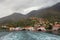 Picturesque Mediterranean village on mountainside next to ferry. Montenegro, Adriatic Sea, Bay of Kotor