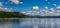 Picturesque panorama lake landscape with forest on the lakeshore and reflections of clouds and sky in the water