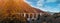 Picturesque panoramic image arched old bridge located in French Pyrenees and rocky mountain range view, blue cloudy sky