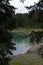 Picturesque peaks of Dolomites mountains in reflection of crystal clear pond surrounded by coniferous forest. Lake of Caresse in