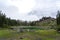 Picturesque peaks of Dolomites mountains in reflection of crystal clear pond surrounded by coniferous forest. Lake of Caresse in