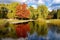Picturesque pond in beautiful autumn park. Colorful trees and fluffy clouds reflected in smooth surface water
