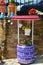 Picturesque Pots Decorated As Two Young Asturians Next To A Well Of Water Also Decorated With Violet Tires In Taramundi, Asturias,