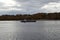 A picturesque river. Autumn forest near the village. Motor ship, buoy. Clouds