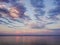 Picturesque river landscape. Sunny sunset. Pink clouds on the blue sky. Sailboat on the horizon