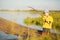 Picturesque scene of cute little boy fishing from wooden dock on magical lake at sunny summer day, vivid colors