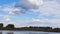 A picturesque skyline in summer with beautiful clouds reflecting in the water and trees on the horizon