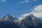 Picturesque snow-covered rocky peaks of the mountains of the Zailiysky Alatau in the daytime on a warm clear summer day.