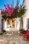 Picturesque street with white ancient greek houses and vibrant flowers of pink bougainvillea in old Afionas village on