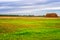 Picturesque summer landscape with beveled meadow and haystacks in cloudy morning. Hay harvest at farmland. Beautiful agricultural