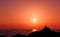 Picturesque sunset on the beach with a man sitting on a rock