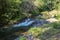 Picturesque valley in mountains and calm river. Boulders in the riverbed and rocks along the valley.