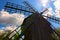 Picturesque view of ancient wooden wind mill against blue sky with sun shining. Museum of Folk Architecture and Life.