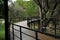 Picturesque view of bridge with metal railing and many trees in park