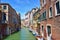 Picturesque view of narrow Venetian canal with anchored boats