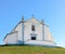 Picturesque view of a Portuguese Catholic church on a lush green lawn against a blue sky