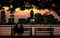 Picturesque view of a sunset over the city skylines and a couple's silhouettes sitting on a bench