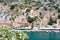 Picturesque view on tiny colorful houses on rocks through blooming white oleander tree near the Mediterranian sea on Greek island