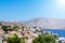 Picturesque view on tiny colorful houses on rocks, green trees near the Mediterranian sea on Greek island in sunny summer day with