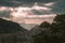 Picturesque view to the ancient mountain town with fortress wall under sunlights shining through the stormy clouds