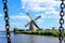 A picturesque view on a vintage windmills through the bridge chains on a sunny day with blue clouded sky