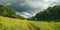 Picturesque and winding hills with fields, roads and dramatic pre-storm skies. Large panorama