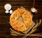 Pie on sacking, wooden background. Baking ingredients: flour, eggs, salt and ears