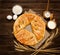 Pie on sacking, wooden background. Baking ingredients: flour, eggs, salt and mug of milk, ears.