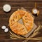 Pie on sacking, wooden background. Baking ingredients: flour, eggs, salt and mug of milk, ears. View from above