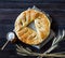 Pie with sesame on a sacking, ears of wheat and salt. Dark wooden background, top view