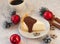 A a piece of an appetizing cheese cake with melted chocolate on it, a cup of coffee, silver cones, cinnamon sticks and Christmas-t