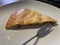 A piece of apple pie on a white plate with a dessert fork