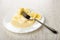 Piece of banana strung on fork in plate with slices of banana and condensed milk on table