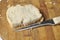 A piece of bread and a knife on a wooden board isolated on a white background