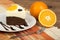 A piece of brownie cake with cream and oranges.