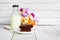 Piece of brownie cake on white small plate with bottle of fresh milk on wooden table and with brick wall with copy space